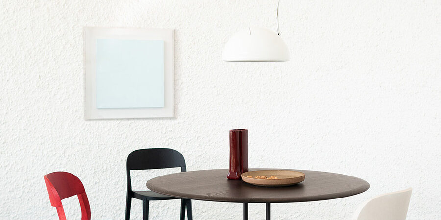 Sedie spaiate Minima di Potocco in colori diversi intorno a un tavolo rotondo