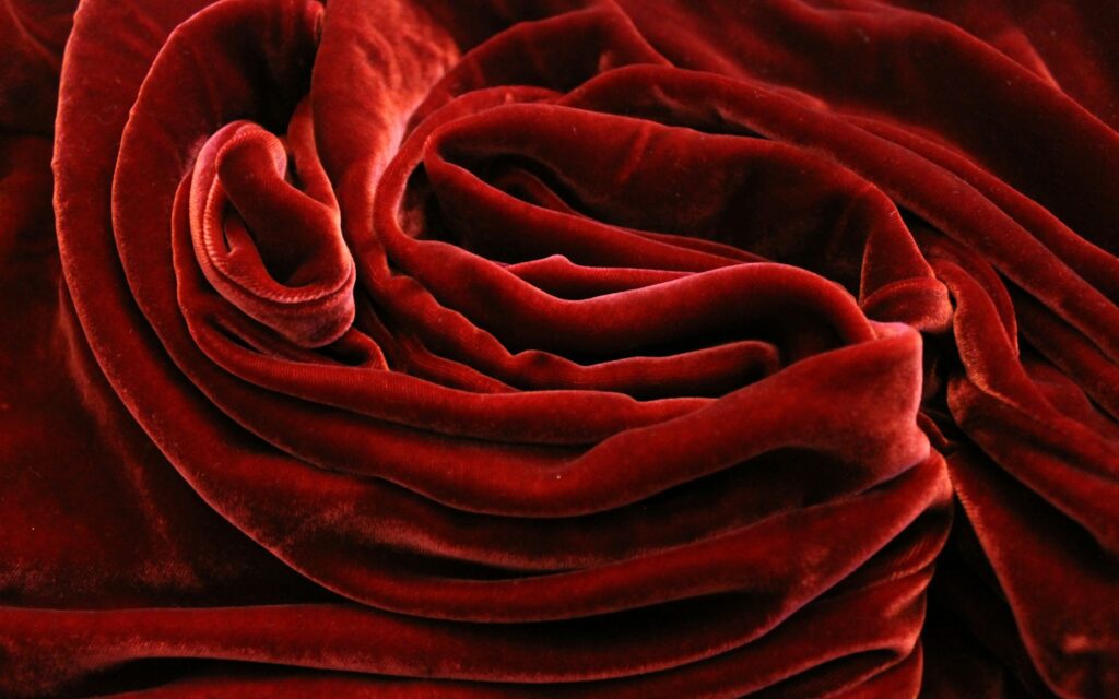 Velluto rosso drappeggiato con pelo che riflette la luce in modo diverso