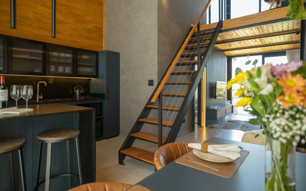 Cucina in stile loft con sgabelli in metallo alla penisola e scala in ferro